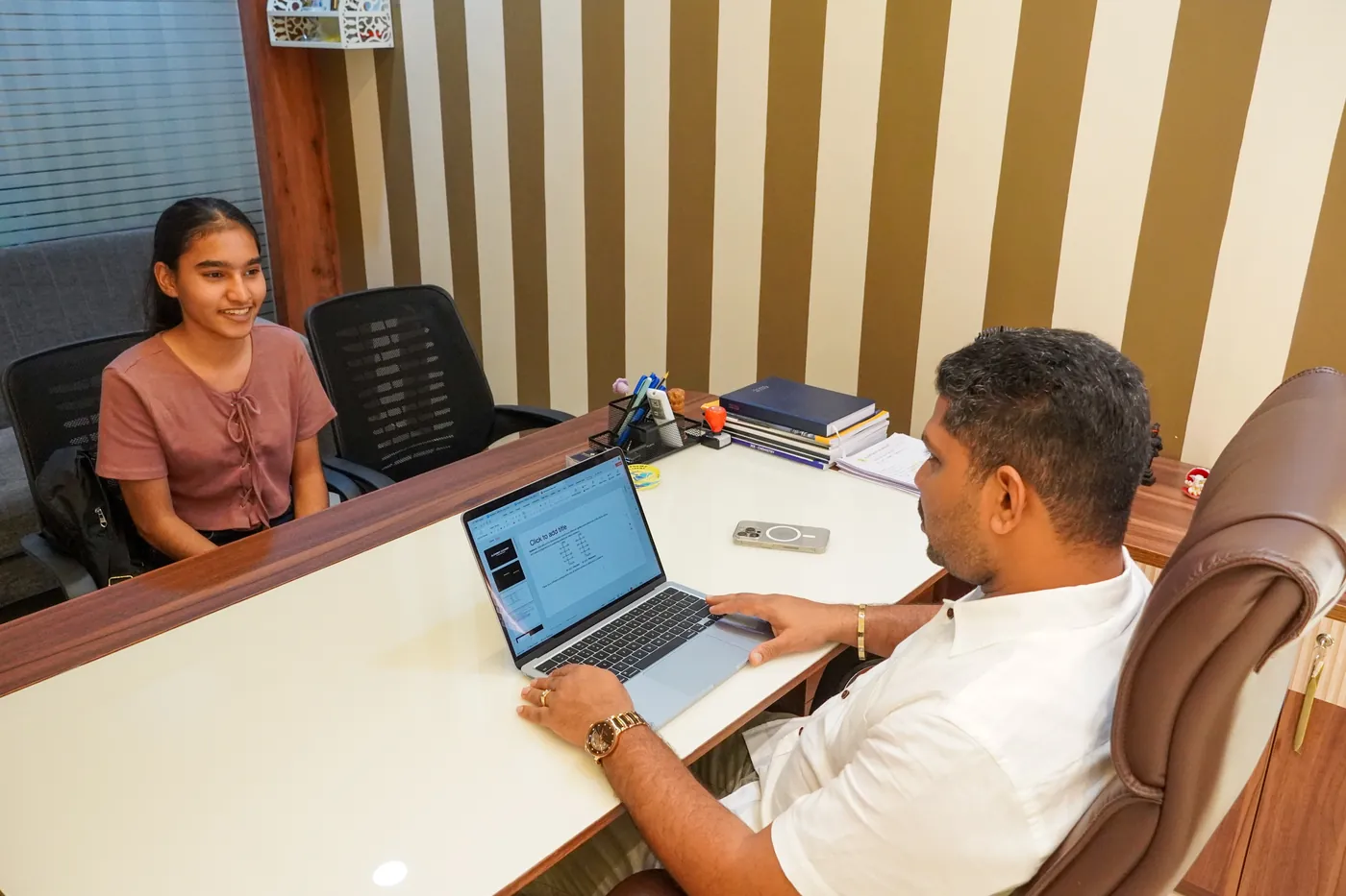 Director mentoring a student over study material at Alchemist Academy